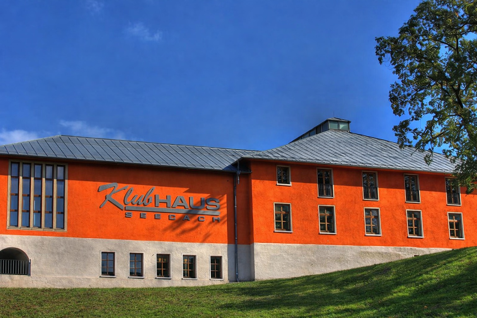 Das orangefarbene Klubhaus Seebach unter blauem Himmel